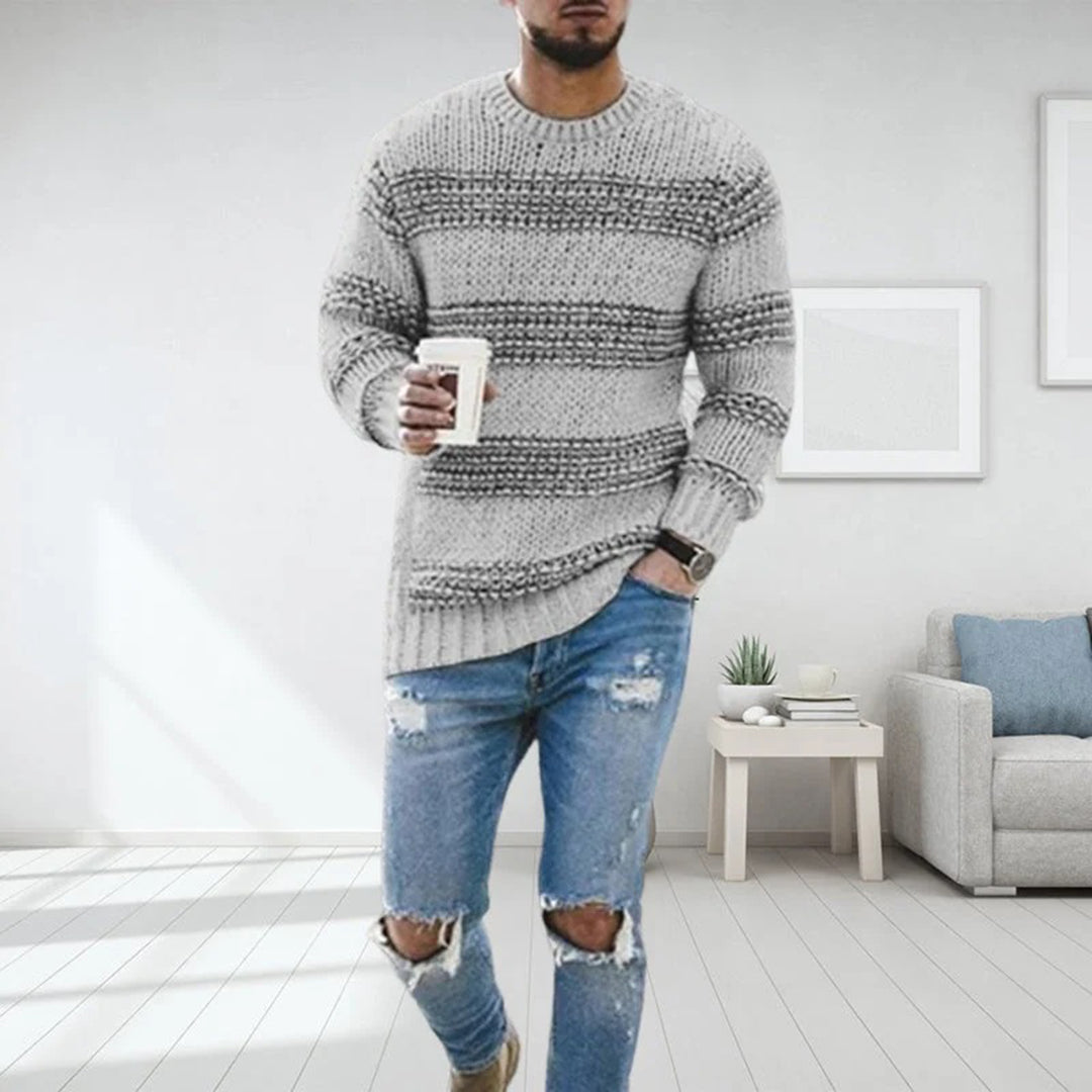 Mann i blå strikkegenser med kaffekopp, slitte jeans, moderne stue. Mote, komfortabel stil, herreklær, interiørdesign.