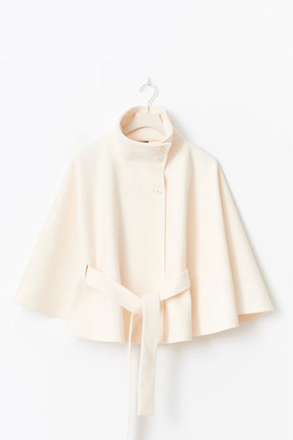 Creme kleurige cape jas met hoge kraag en knoopsluiting – close-up voorkant